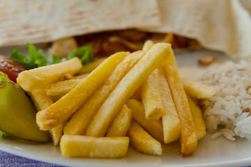 close up of french fries, rice and shawarma on plate