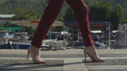 beautiful legs of business woman in the shoes go on the pier on the background of beautiful nature.