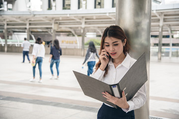 Portraits of beautiful asian woman look confidence is standing and holding cellphone . she using smartphone calling to conversation with customer.