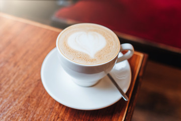 Drinking morning coffee. Hot latte in white cup. Coffee lover concept. Cappucino with beautiuful heart on foam. Cacao and latte art. Pattern on milk foam. Hot beverage
