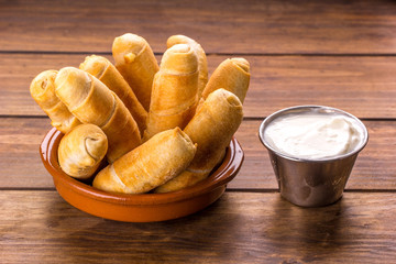 Tequeños, Typical Venezuelan snack with garlic sauce on a wood background