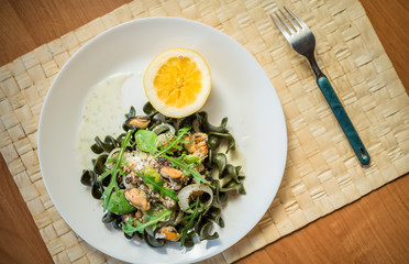 Black pasta with seafood in white cream sauce and lemon