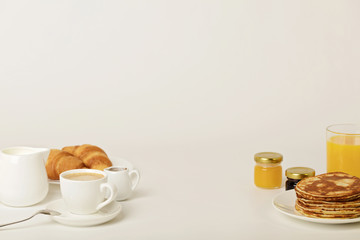 Breakfast - coffee with croissants, juice with pancakes on a white background.