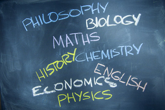 Education concept: Names of school subjects inscribed on a black chalkboard with colored chalks