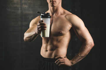 Obraz na płótnie Canvas Handsome athletic fitness man holding a shaker and posing gym