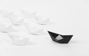 creative black paper ship among white. concept leadership different.