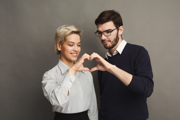 Happy couple in love showing heart with their fingers