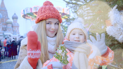 Beautiful mom and little boy are smiling at the Christmas fair in the city