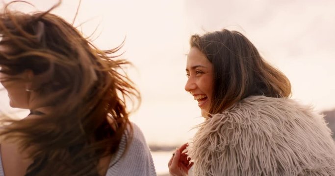 Two beautiful girls laughing together at sunset