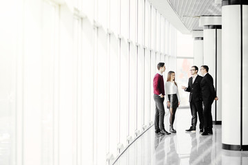 The business people walk in the office hall on the window background