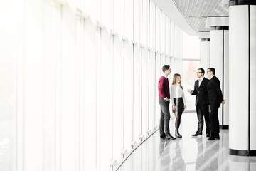Fototapeta premium The business people walk in the office hall on the window background