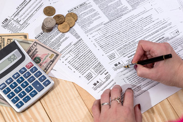 Naklejka premium a woman writes a tax return 1120 w 4 on a wooden table