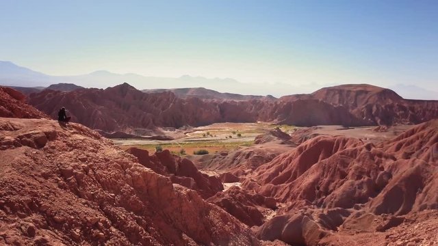Aerial shot of female trekker standing at the cliff contemplating the horizon of the Atacama desert. 4k