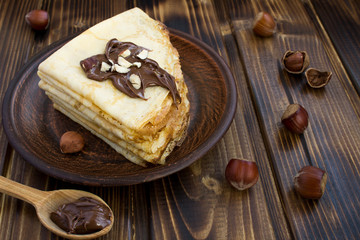 Homemade crepes with chocolate and nuts on the brown  plate