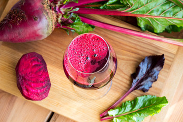 Red beet juice in a wine glass on a wooden table
