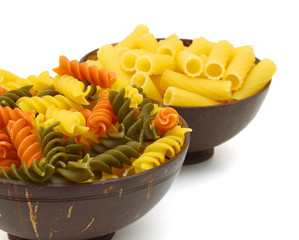close up of a dried italian pasta in wood bowl on white background