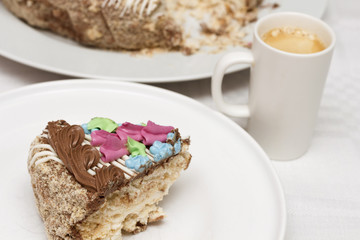 Cake with cream, nuts and meringue with cup of coffee