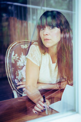 Writing woman looking outside a window