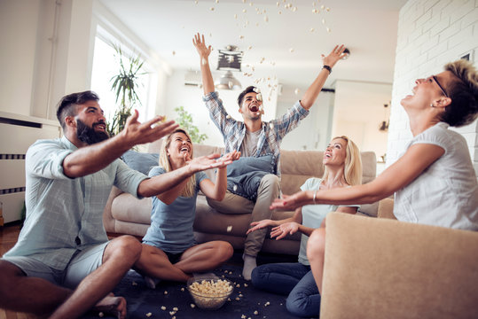Attractive young people throwing popcorn and enjoying together.