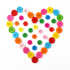 Fototapeta premium Heart shaped of colorful sewing buttons on white