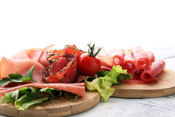 Food tray with delicious salami, pieces of sliced ham, sausage, tomatoes, salad and vegetable - Meat platter with selection