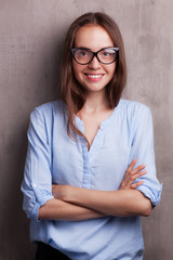 portrait of beautiful happy young woman wearing glasses near grey grunge wall