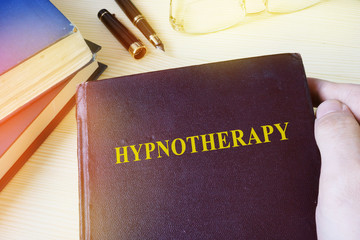 Man holding book with title Hypnotherapy.
