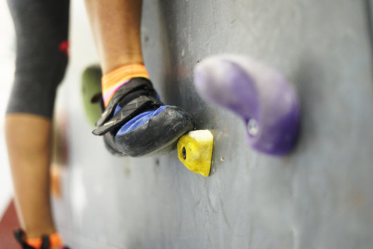 Climbing rocks on climbing wall. Fitness, extreme sport, bouldering, people and healthy lifestyle concept - people exercising at indoor climbing gym. Close-up image