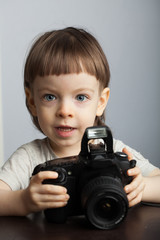 Beautiful child in with professional camera. Little boy with long blond hair photographing in the Studio