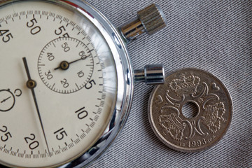 Obraz na płótnie Canvas Denmark coin with a denomination of two crown (krone) (back side) and stopwatch on gray denim backdrop - business background