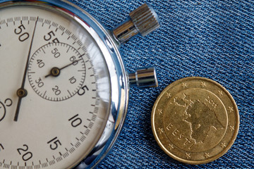 Fototapeta premium Euro coin with a denomination of fifty euro cents (back side) and stopwatch on worn blue denim backdrop - business background