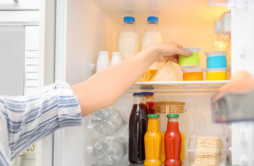 Woman taking yogurt from refrigerator, closeup