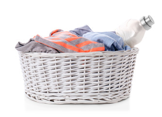 Basket with dirty clothes and laundry detergent on white background