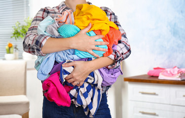 Woman holding pile of dirty laundry, indoors