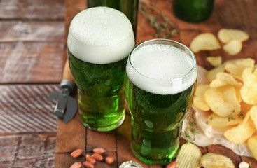 Glasses of green beer and snacks on wooden table. Saint Patrick's day celebration