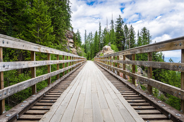 Fototapeta na wymiar Deseterd Wooden Bridge along a Mountain Path on a Spring Day. Myra Canyon, Kelowna, BC, Canada.