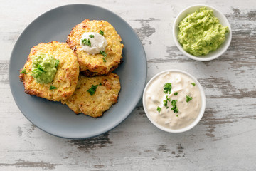healthy vegetable rosti from cauliflower and parmesan cheese with dips from sour cream and avocado,...