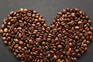 Brown coffee beans in form of heart isolated on black texture background for design, part or half. Saint Valentine's Day card on fabruary 14, holiday concept.
