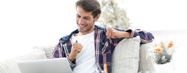 happy guy working with laptop from home. concept of freelancing.
