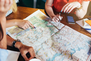 Close-up image of map lying on table and female hands pointing at it - Powered by Adobe