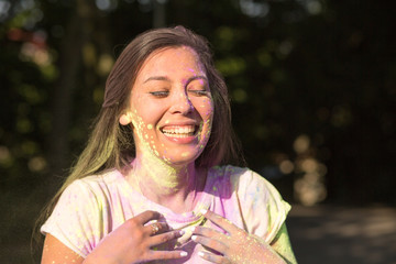 Emotional young asian woman having fun with yellow and purple Holi paint