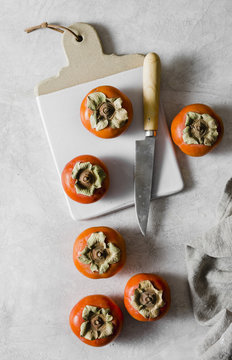Persimmons on a chopping board and grey marble background