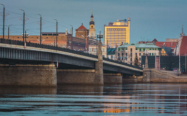 Naklejka premium Picturesque view on the modern architecture of Riga panorama over the river with blue sky in background. Lights creating reflections in river.