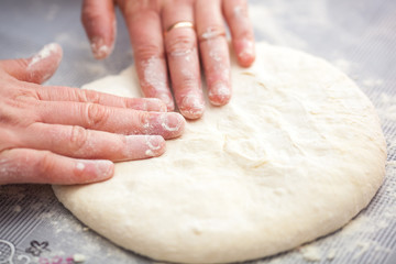 Baker hands preparing khachapuri on kitchen table. View on cook making traditional georgian treat with raw dough