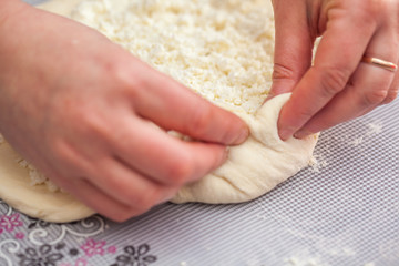 Baker hands preparing khachapuri on kitchen table. View on cook making traditional georgian treat with raw dough
