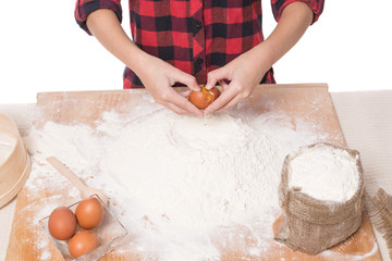 hands of a girl kneading dough on a wooden table, egg in hands