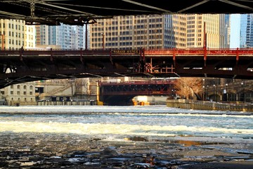 Low angle view underneath bridge of Chicago River, which is frozen with chunks of ice