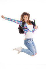 Happy female student jumping with her books and backpack