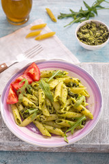 Penne pasta with pesto and arugula in plate on rustic table 