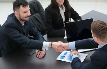 handshake financial partners sitting at the table